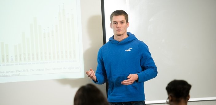 A student giving a presentation at projection screen in class