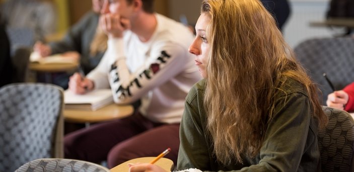 Students listening to the professor and taking notes Students listening to the professor and taking notes