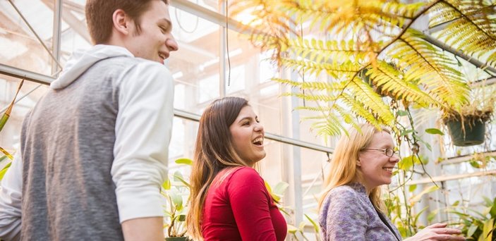 Professor and students in greenhouse surrounded by plants