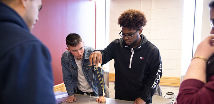 Several students work together to balance objects on a frame.