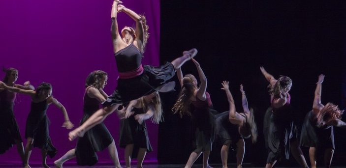 modern dance performance with lead dancer in full leap