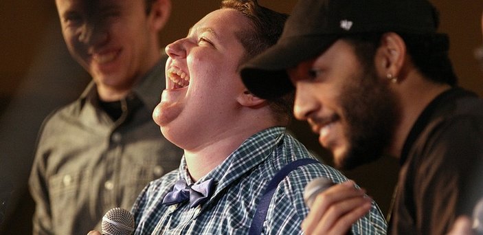 Three students with microphones smiling and laughing