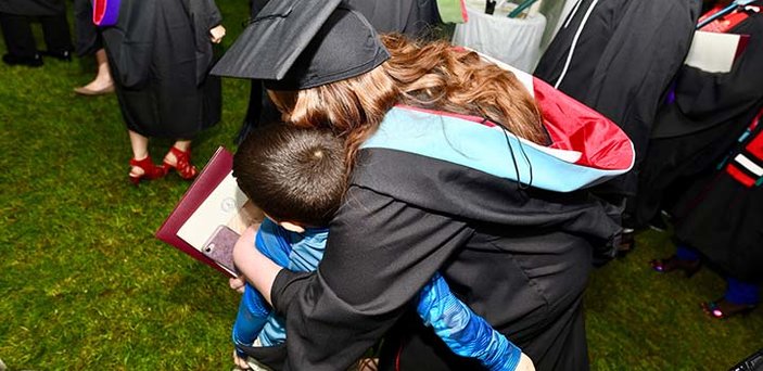 A graduate hugs a boy