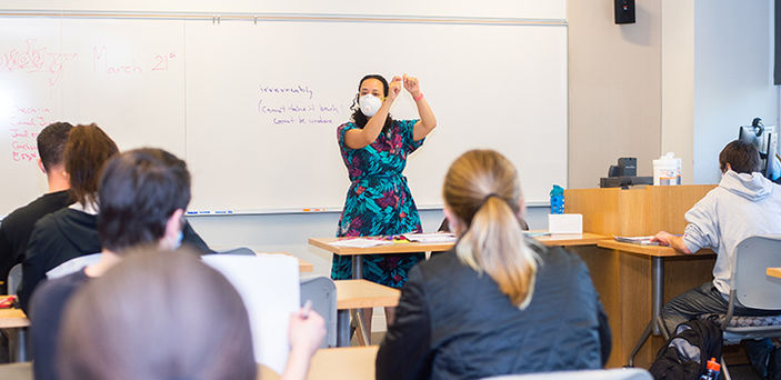 Professor Allyson Ferrante teaches in front of a white board with a definition of "irrevocably" written on it as students look on