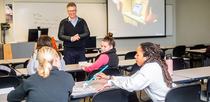 A student practices with an adaptive tool in class while Professor James Feeney and classmates look on