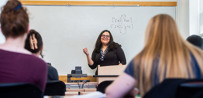 Professor Fernanda Ferreira smiling while teaching Spanish Phonetics in front of a white board while students look on