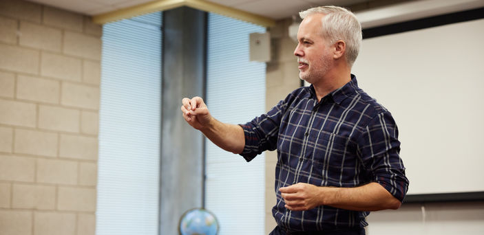 Dr. Matt Bell gestures as he teaches at the front of the class