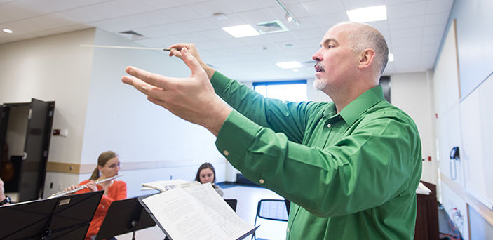 Professor Donald Running conducting flute players in a classroom