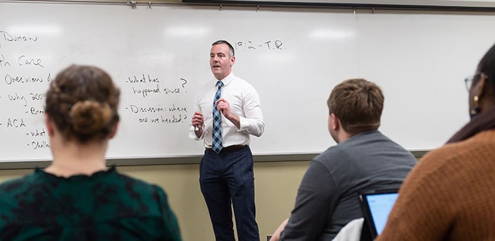 Professor Kevin Donnelly teaching in front of a white board while students look on