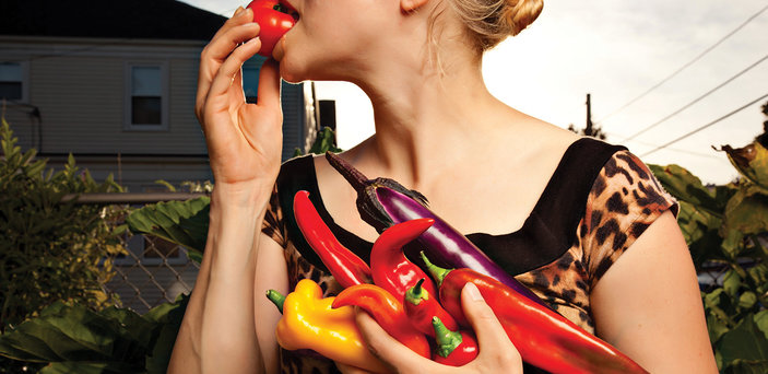 Eating a tomato while holding peppers