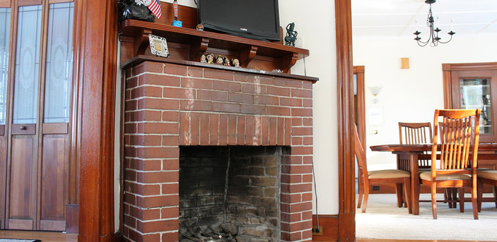 Fireplace in Scholar House living room with tv on top and dining room in background