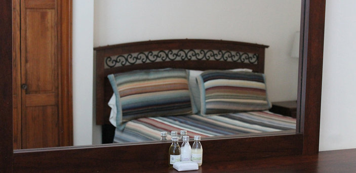 Scholar House bedroom with double bed in reflection of dresser mirror