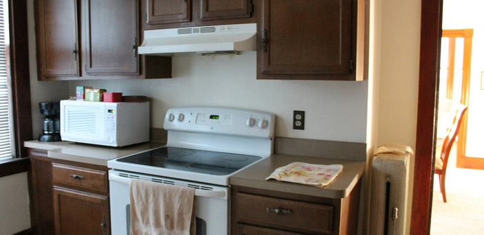 Scholar House kitchen showing stove, microwave, coffee pot, cabinets and counter top