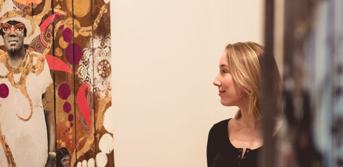 Elizabeth Ezekiel walks between two fence sections in the gallery