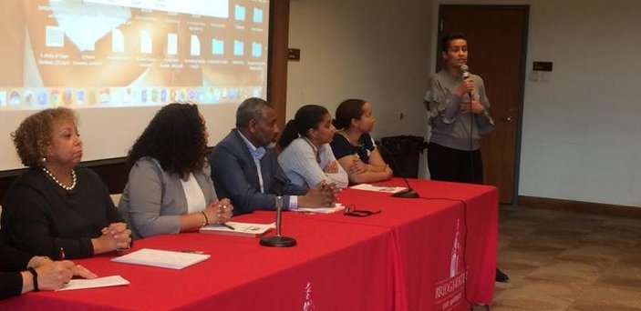 panel at table with speaker standing with microphone