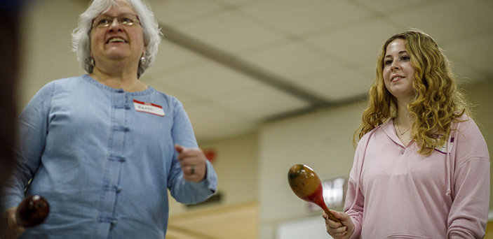 A student and a professor shake maracas.