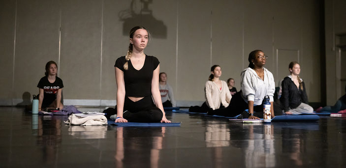 Students sit during a yoga exercise.