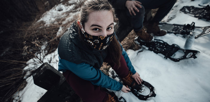 A student adjusts her snowshoe.