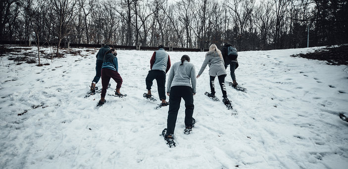 Students snowshoe up a hill.