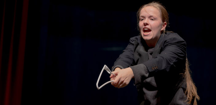 A student acts out a scene using a broken hanger