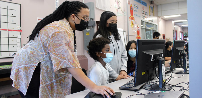 A BSU student helps fifth graders code a robot using a computer program.