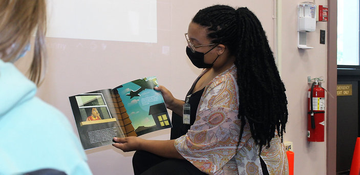 A BSU student reads a book about aviation to children.