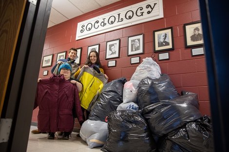 Sociology club stands next to the bags of donations