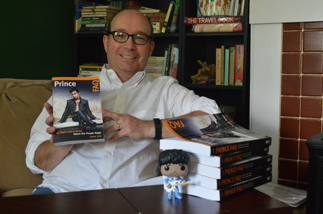 Professor Arthur Lizie holds up his recently published book about musician Prince