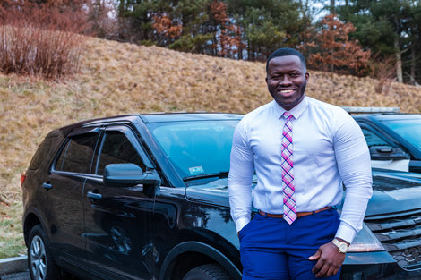 Aboubacar stands next to police cruiser