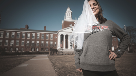 Samantha Moniz, '21 in front of Boyden Hall wearing bridal veil