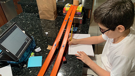 A youngster uses Hot Wheels cars and a track to learn about science from BSU students.