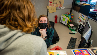 Erin Wentzel helps a student while sitting behind a desk