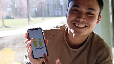 Frankie Raboy, '20 hold cell phone with Handshake ap on screen