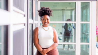 Maya Elysse, '22, poses for a photo in front of windows