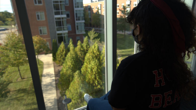 A student sits and looks out window on campus