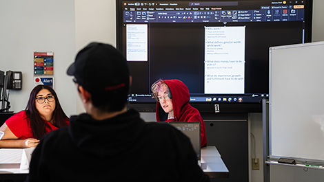 Three students work collaboratively using a large monitor.