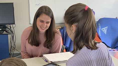Adlai Greene works with a female student at a table.