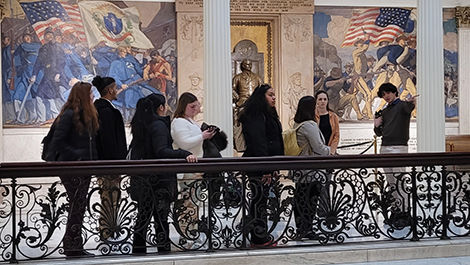 Students on the alternative spring break program walk by a mural inside the Statehouse