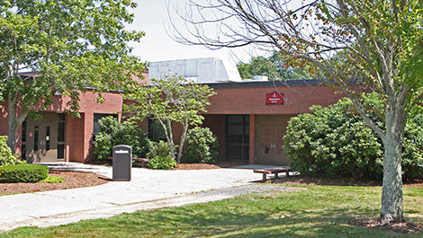 Burnell Hall as seen in summer with several trees in front of the building.