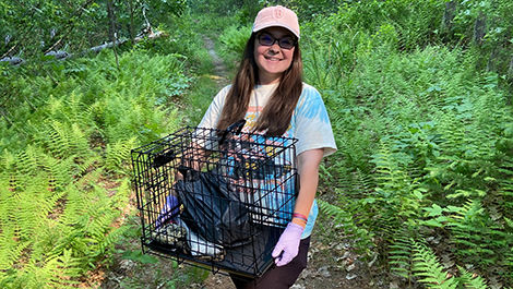 While walking in the woods, Sarah Calis holds a crate used for her research.