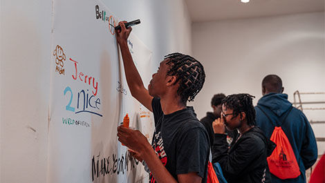 A charter school student makes a design on paper hung on a wall.