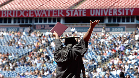 A graduate raises their hands in front of a crowd.