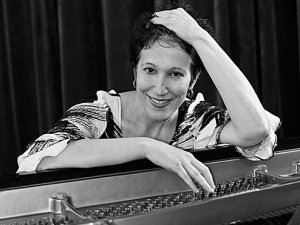Deb Nemko poses sitting at her piano