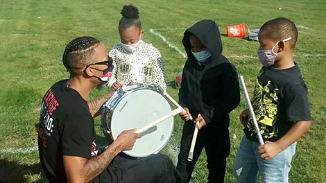 Greg Fernandes gives a drum lesson to three kids.