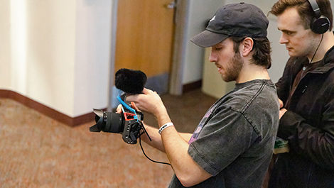 Two students work with a camera in a class about film festival production.