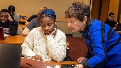 Evie Dewar works with a first-generation student on a laptop.