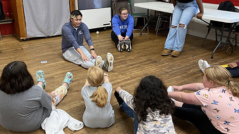 BSU students teach a stretching exercise to girls