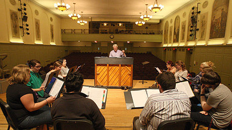 A chorus rehearses on the Horace Mann Auditorium stage.
