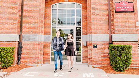 Caitlin and Joe hold hands while walking in front of Woodward Hall.