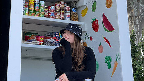 Kellie sits in front of shelves filled with food.